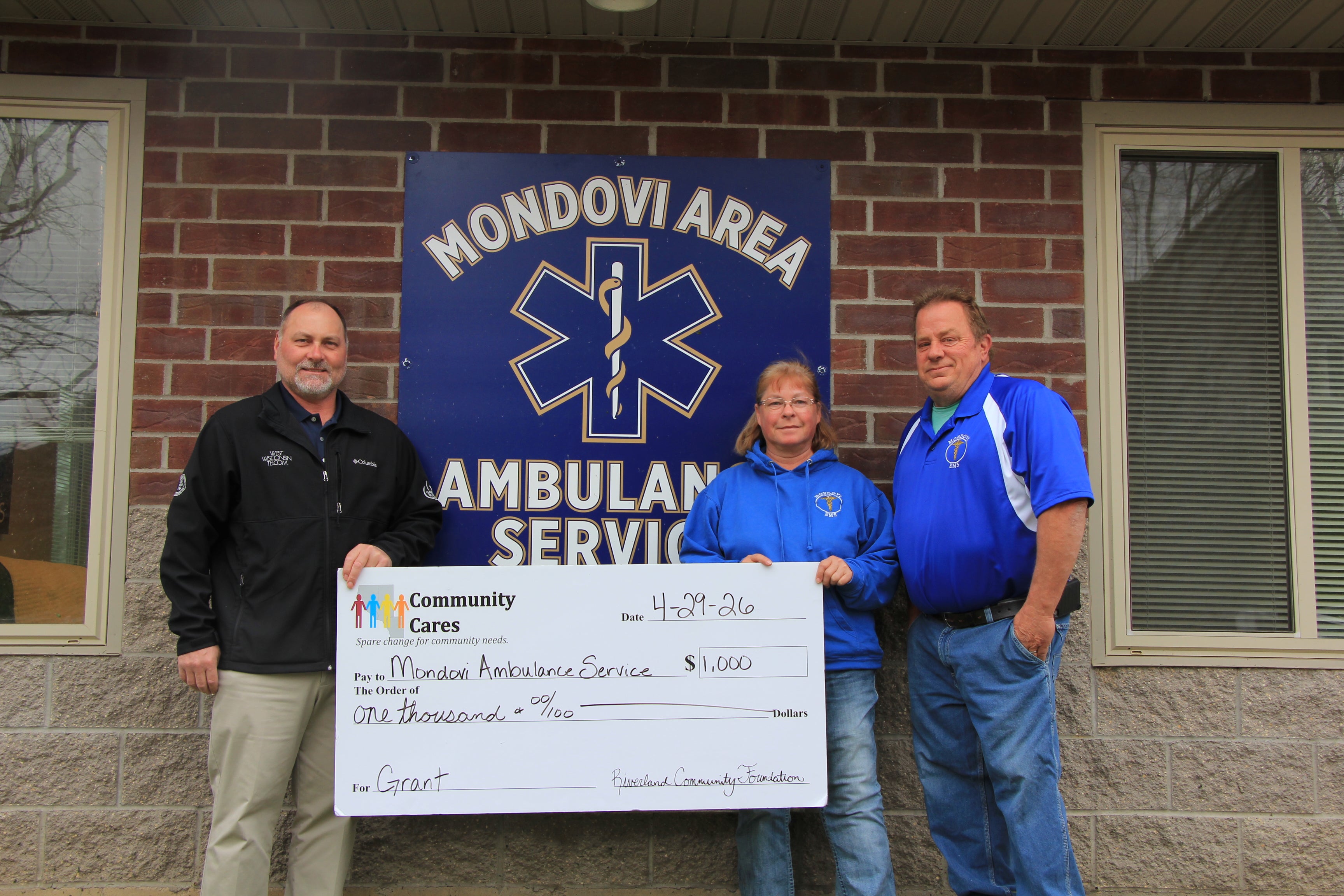Director Brad Schmidtknecht standing with two representatives from the Mondovi Ambulance service holding a giant donation check from our Community Cares Grant. 